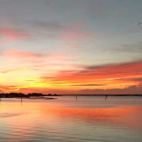 A serene sunset over calm waters, with vibrant orange and pink hues reflecting on the surface.