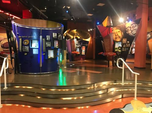 Exhibit space with colorful displays and informational panels in a museum setting, featuring unique architectural elements.