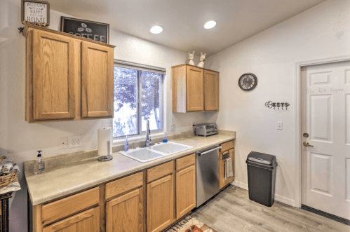 Bright kitchen with wooden cabinets, a double sink, stainless steel appliances, and a door leading outside.