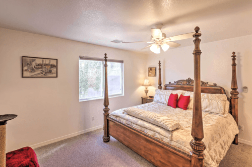 Cozy bedroom featuring a four-poster bed, soft bedding, a ceiling fan, and a window with natural light.