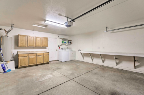 A spacious, clean garage with wooden cabinets, a washing machine, and a long workbench against the wall.