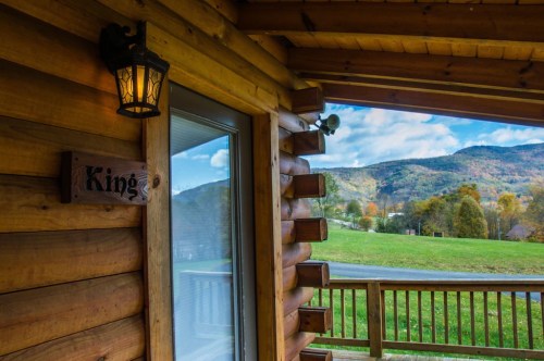 A wooden cabin with a lantern, sign reading "Kings," and a view of green hills and blue sky in the background.