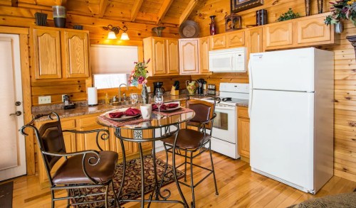 Cozy wooden kitchen with a round table, chairs, and modern appliances, featuring warm lighting and rustic decor.
