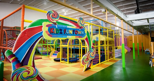 Colorful entrance to Kidz Funtown, featuring play structures and soft play areas in a vibrant indoor setting.