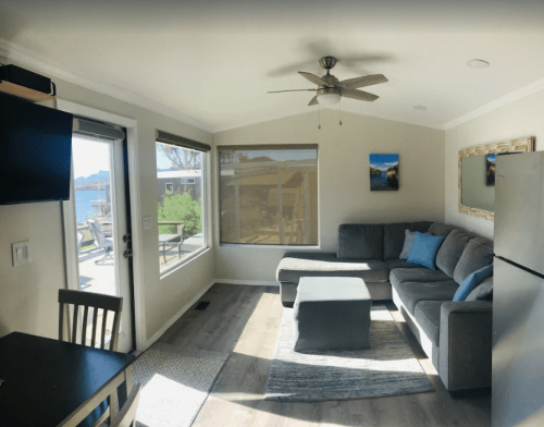 Cozy living room with a gray sectional sofa, coffee table, and large windows overlooking a scenic view.