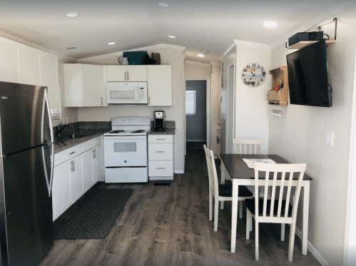 Modern kitchen with white cabinets, stainless steel appliances, a dining table, and a cozy, bright atmosphere.