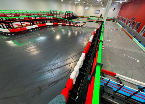 A wide view of a go-kart track featuring colorful barriers and smooth asphalt, with multiple winding lanes.
