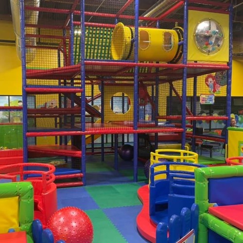 Colorful indoor play structure with slides, climbing areas, and soft play equipment in a vibrant children's play area.