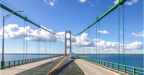 Stunning Mackinac Bridge views of the Straits connecting to Lake Michigan, with land in the distance.