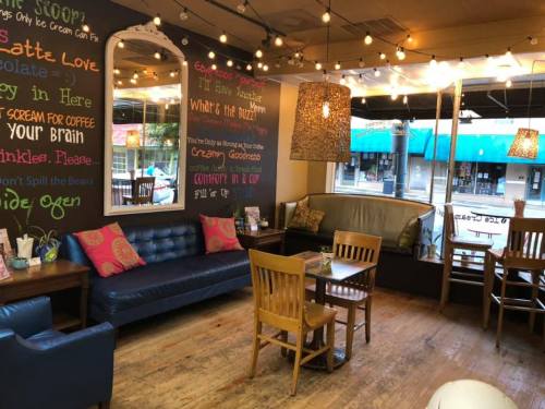 Cozy café interior with colorful decor, a mirror, string lights, and wooden furniture, creating a warm atmosphere.