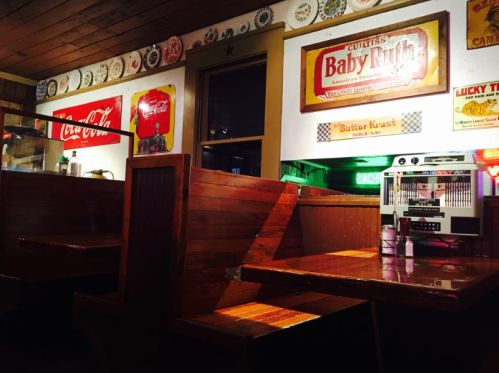 A cozy diner interior featuring wooden booths, vintage signs, and a jukebox, creating a nostalgic atmosphere.