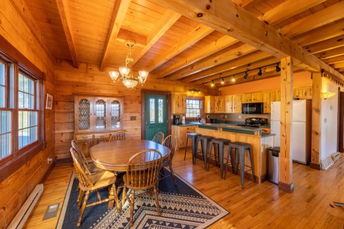 Cozy wooden kitchen and dining area with a round table, bar stools, and warm lighting.