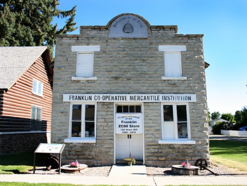 Historic stone building with white shutters, labeled "Franklin Co-Operative Mercantile Institution," in a rural setting.