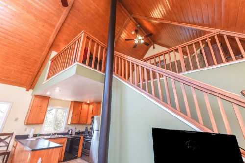 A cozy interior of a home featuring a wooden ceiling, open staircase, and modern kitchen appliances.