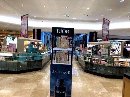 A spacious retail area featuring Dior and Sauvage displays, with various beauty products on glass shelves.