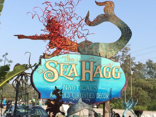 Colorful sign for "The Sea Hagg" featuring a mermaid and whimsical design, promoting nauticals, antiques, and curiosities.