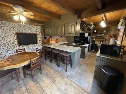 Cozy kitchen with wooden accents, granite countertops, a dining table, and modern appliances in a rustic setting.