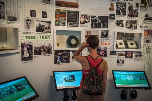 A person examines a wall display of historical music artifacts and information in a museum setting.