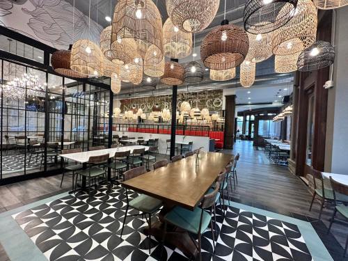 A modern restaurant interior featuring woven pendant lights, wooden tables, and a patterned floor.