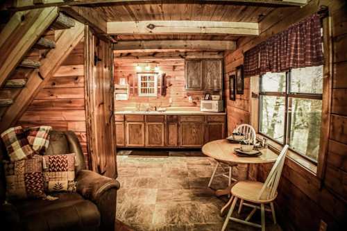 Cozy wooden cabin interior featuring a kitchen, dining area, and comfortable seating with rustic decor.