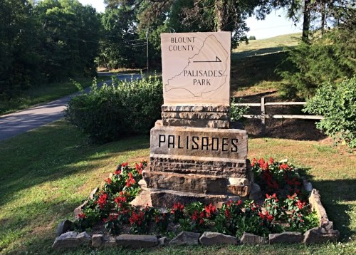 Sign marking the entrance to Palisades Park in Blount County, surrounded by flowers and greenery.