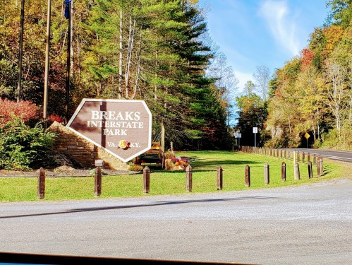 Sign for Breaks Interstate Park surrounded by colorful autumn foliage and a clear blue sky.