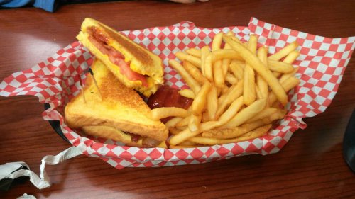 A basket with a grilled cheese sandwich and a side of golden French fries, served with ketchup.