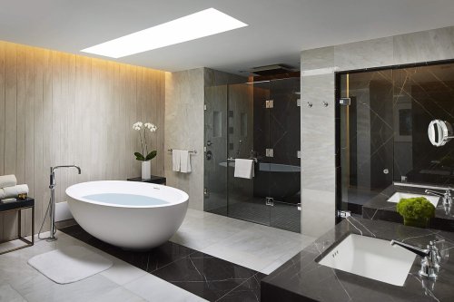 Modern bathroom featuring a freestanding tub, glass shower, and elegant marble finishes. Bright and spacious design.