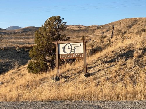 A wooden sign pointing towards "Ringing Rocks" in a dry, grassy landscape with hills in the background.