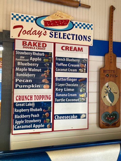 Menu board displaying today's pie selections: baked, cream, and crunch topping options. Includes flavors like strawberry, blueberry, and cheesecake.
