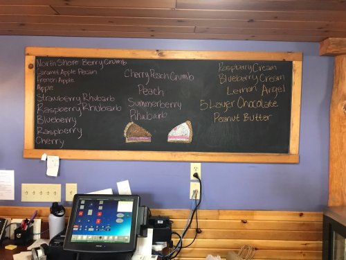 Chalkboard menu listing various pie flavors, including Cherry Peach Crumb, Raspberry Cream, and Peanut Butter.