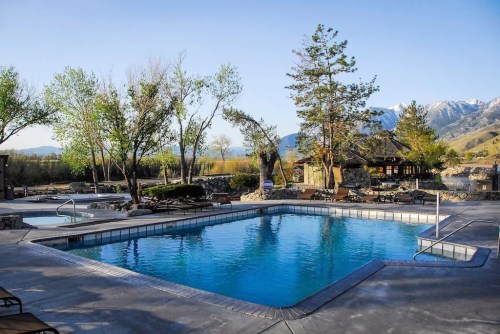 A serene outdoor pool surrounded by trees and mountains, with clear blue water and a relaxing atmosphere.