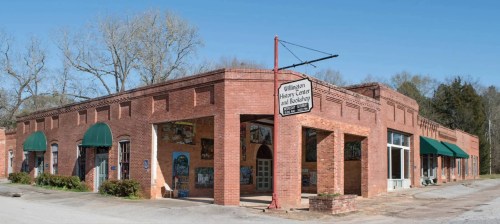 Historic brick building with green awnings, featuring murals and a sign for the Williamson History Center and Museum.