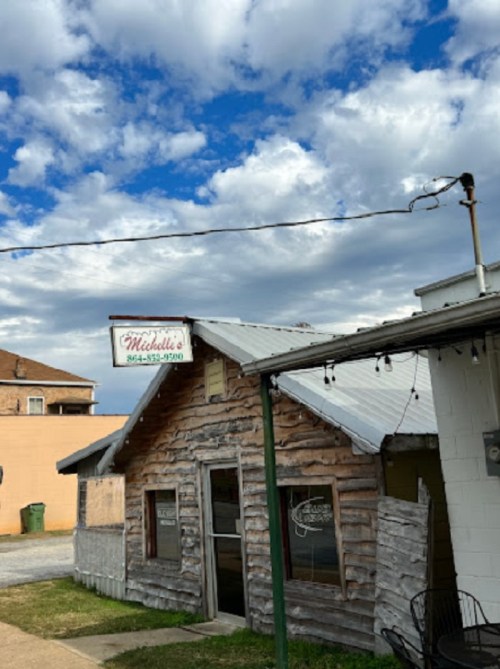 A rustic wooden building with a sign reading "Mitchell's" under a partly cloudy sky.