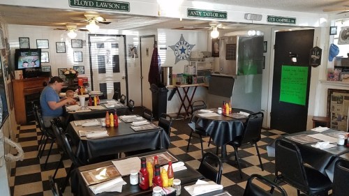 A cozy diner with checkered floors, tables set with condiments, and a family enjoying a meal in a casual atmosphere.