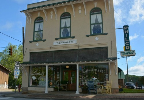 Historic building with a café sign, featuring large windows and decorative details, located at a street intersection.