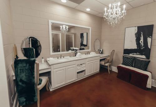 Elegant bathroom featuring a double vanity, chandelier, and modern decor with plush seating and stylish artwork.