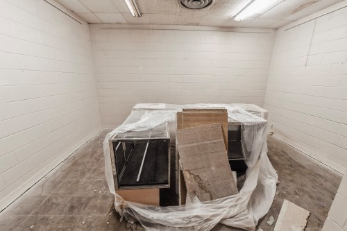 An empty room with white walls, featuring a covered table and debris scattered on the floor.