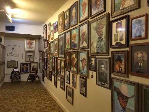A hallway lined with framed portraits of cowboys, showcasing various styles and expressions on the walls.