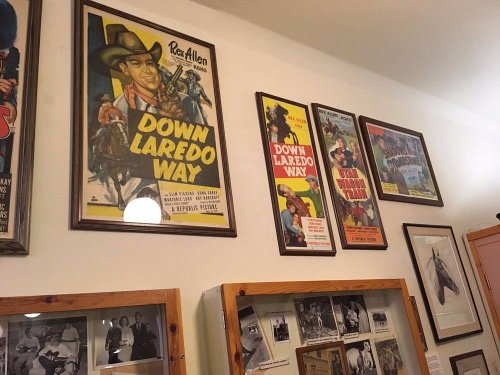 A wall displaying framed vintage movie posters, including "Down Laredo Way," alongside black-and-white photographs.