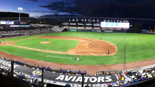 A panoramic view of Las Vegas Ballpark during a baseball game, with a crowd and illuminated scoreboard.