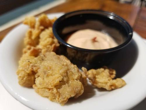 A plate with crispy fried chicken pieces and a small cup of dipping sauce.