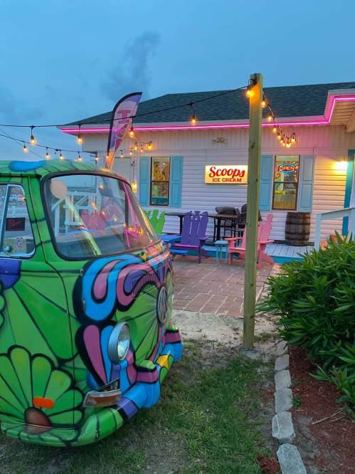 A colorful vintage van parked outside "Scoops Ice Cream," with string lights and a charming ice cream shop ambiance.