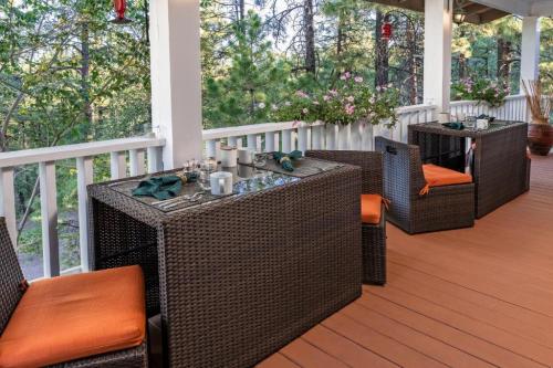 Cozy outdoor dining area with wicker tables and orange cushions, surrounded by greenery and flowers.