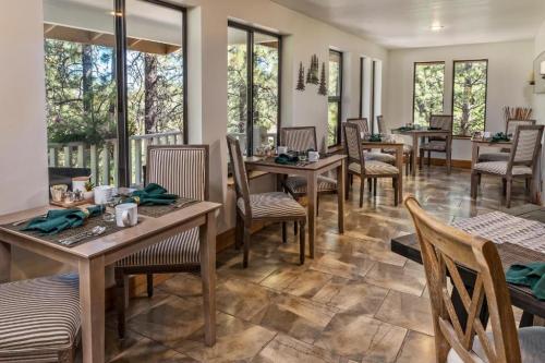 Cozy dining area with wooden tables and chairs, surrounded by large windows showcasing a forest view.