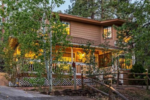 A cozy two-story house surrounded by trees, with warm lights glowing from the windows and a welcoming porch.