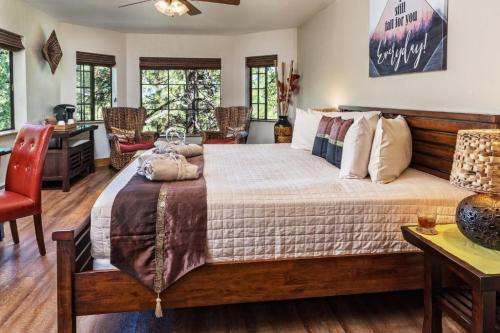 Cozy bedroom with a large bed, wooden furniture, and windows overlooking greenery, featuring warm decor and seating area.