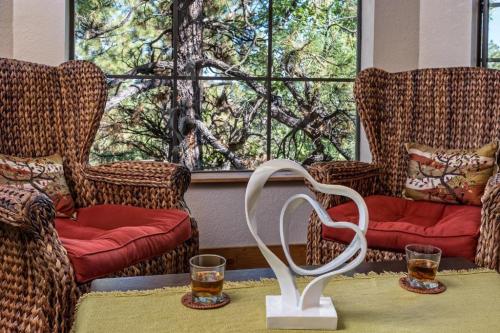 A cozy seating area with woven chairs, a heart sculpture, and glasses on a table, framed by a view of trees outside.