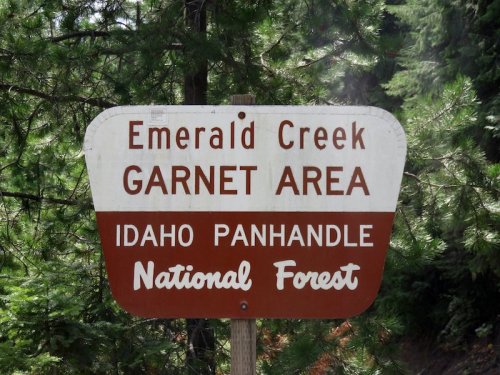 Sign for Emerald Creek Garnet Area in Idaho Panhandle National Forest, surrounded by green trees.
