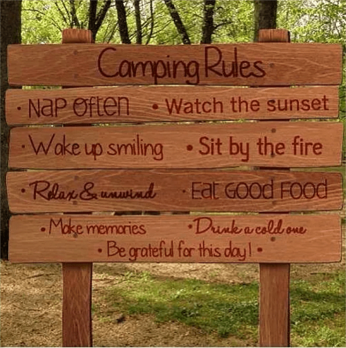 Wooden sign with camping rules: nap often, watch the sunset, sit by the fire, relax, eat good food, and make memories.